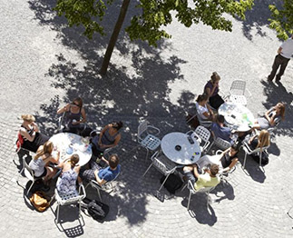 Personen sitzen draussen an runden Tischen