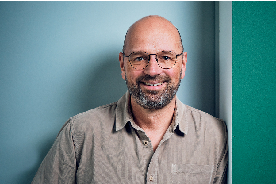 Ein Mann mit Bart und Brille lächelt.