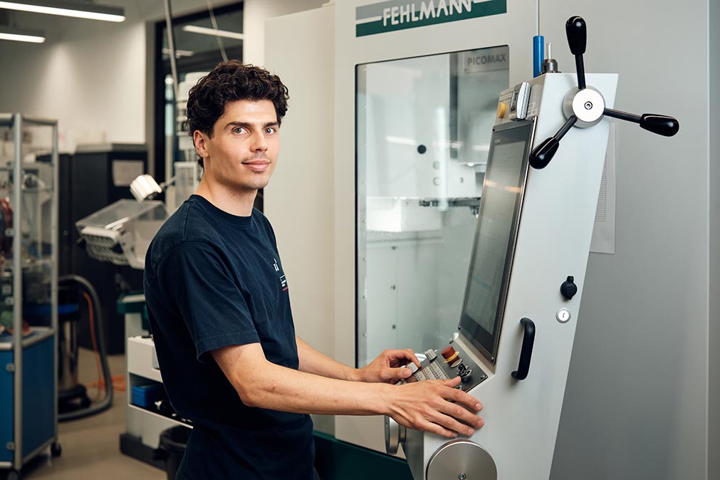 Ein junger Mann bedient eine Maschine in einer Werkstatt.