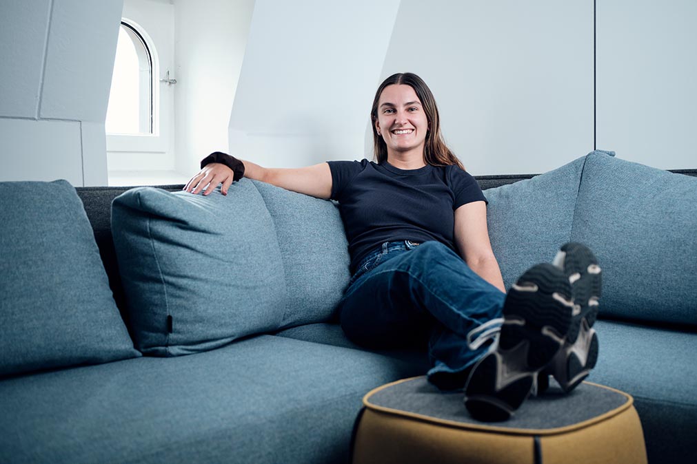 Eine Frau sitzt auf einem Sofa mit Füssen auf einem Beistelltisch.