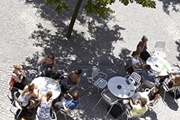 Personen sitzen draussen an runden Tischen