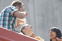 Drei Personen essen stehend draussen