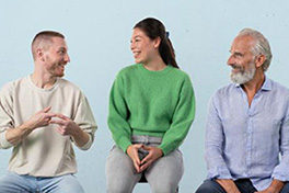 Drei lachende Personen, die nebeneinander sitzen