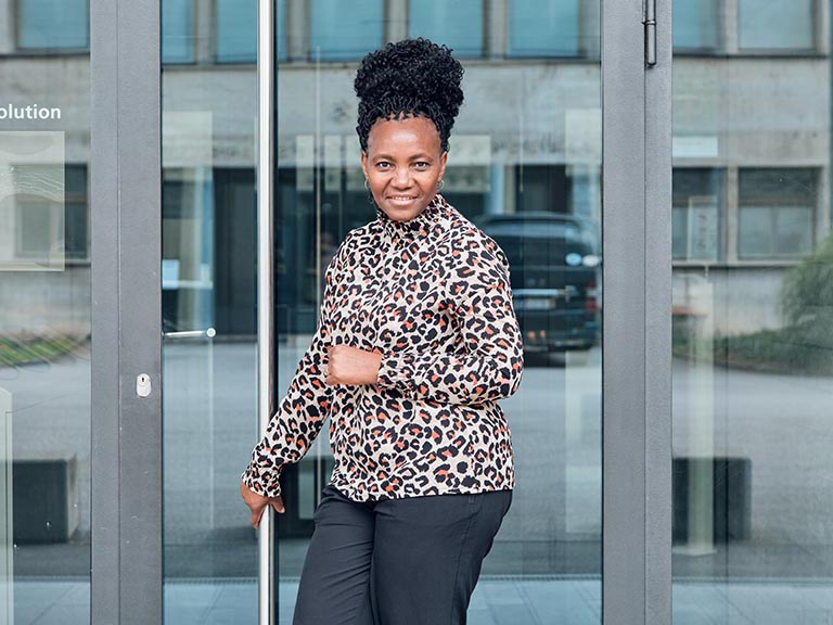 Frau vor der Eingagstüre eines Gebäudes.