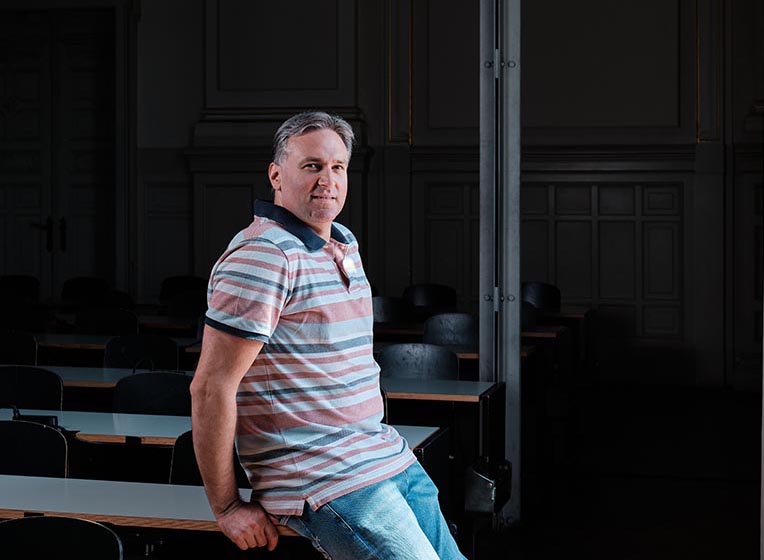 Ein Mann sitzt auf einem Schreibtisch in einem Schulungsraum.