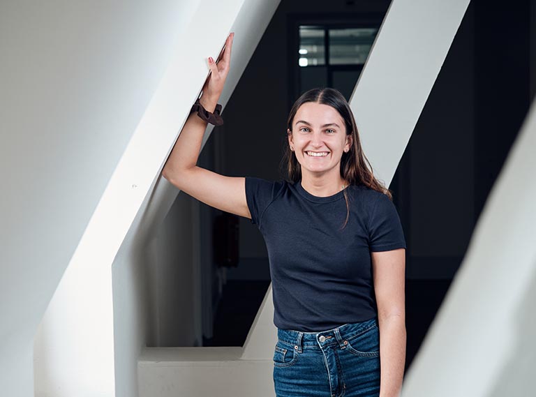 Eine lächelnde Frau hält sich seitlich an einer Dachschräge.